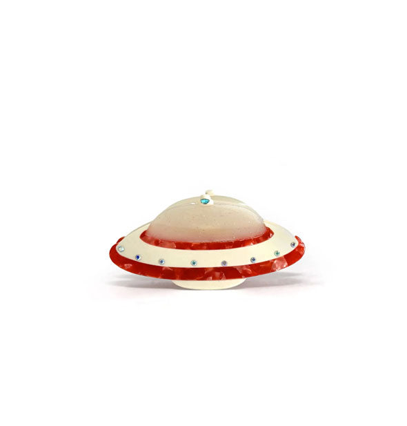 Hair clip designed to resemble a spaceship with glittery top, pearlescent red edges, and rhinestone details