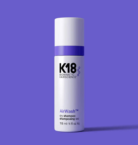 White 4 ounce bottle of K18 Biomimetic Hair Science AirWash Dry Shampoo with purple stripe on a purple backdrop