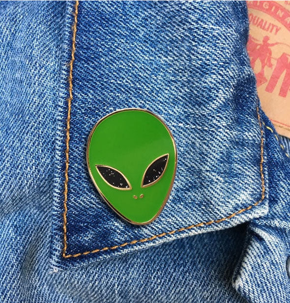 Green alien pin on jean jacket lapel