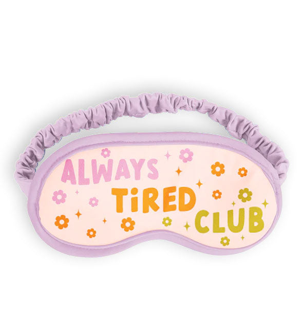 Sleep mask with purple piping and ruched elastic band says, "Always Tired Club" in purple, orange, and olive green lettering accented with color coordinating daisies and stars