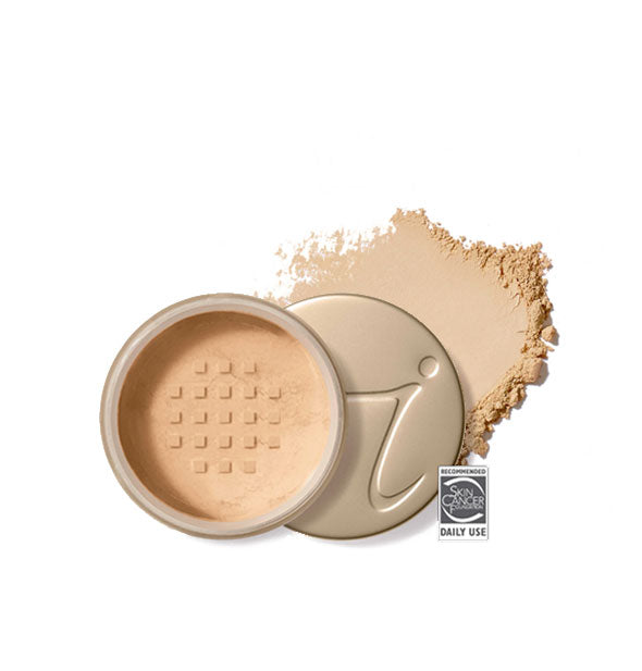 Opened round Jane Iredale loose powder compact with stamped gold lid and product application behind it in shade Amber