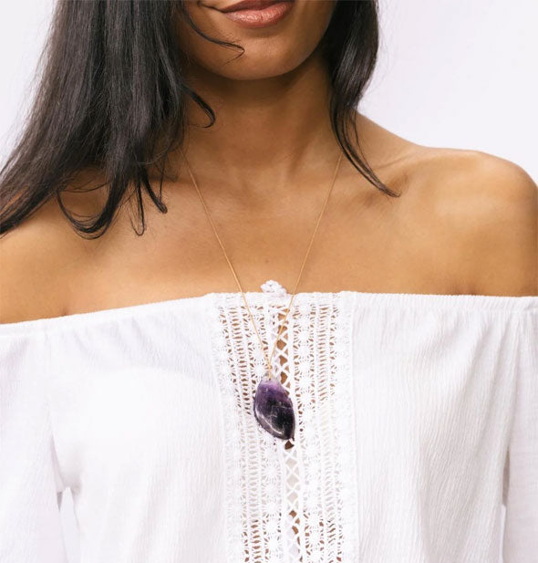 Model wears a purple amethyst stone necklace at a longer length near bustline