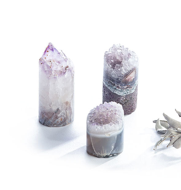 Three cylindrical amethyst crystals with varying layers, points, and mineral deposit patternings