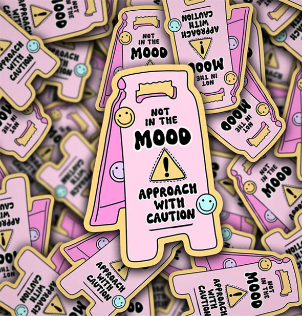 Pile of stickers with pink floor sign illustration accented by pastel smiley faces and the message, "Not in the mood. Approach with caution"