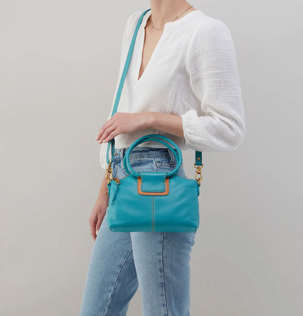 Model wears an aqua blue Sheila Crossbody handbag over shoulder