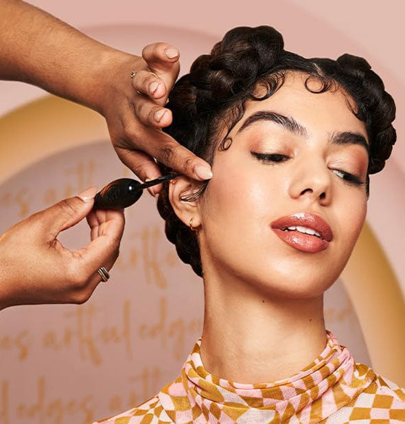 Stylist shapes a model's baby hairs into structured, flat-laying swirls