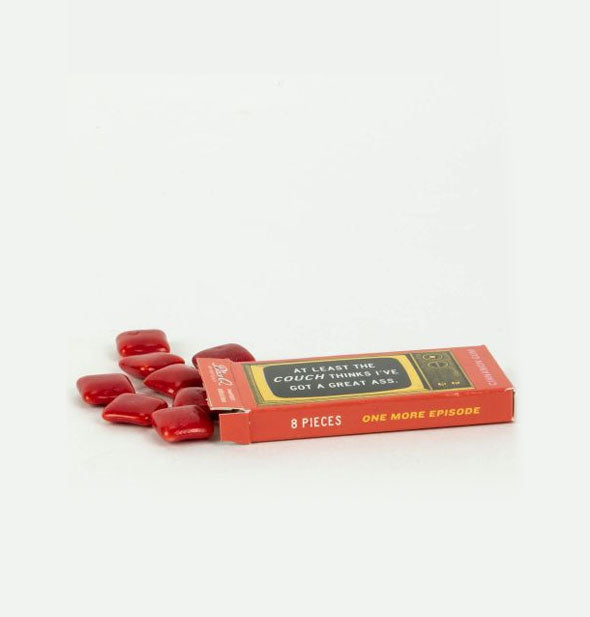 Orange gum pack lays on its side spilling out candied red gum squares