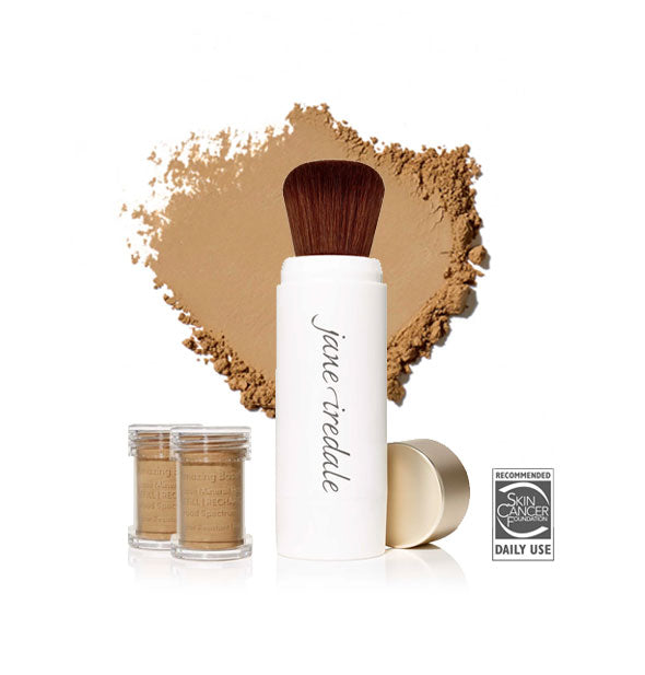 White Jane Iredale powder brush with gold cap removed and set to the side, two refill canisters nearby, and an enlarged product sample in the background in shade Autumn