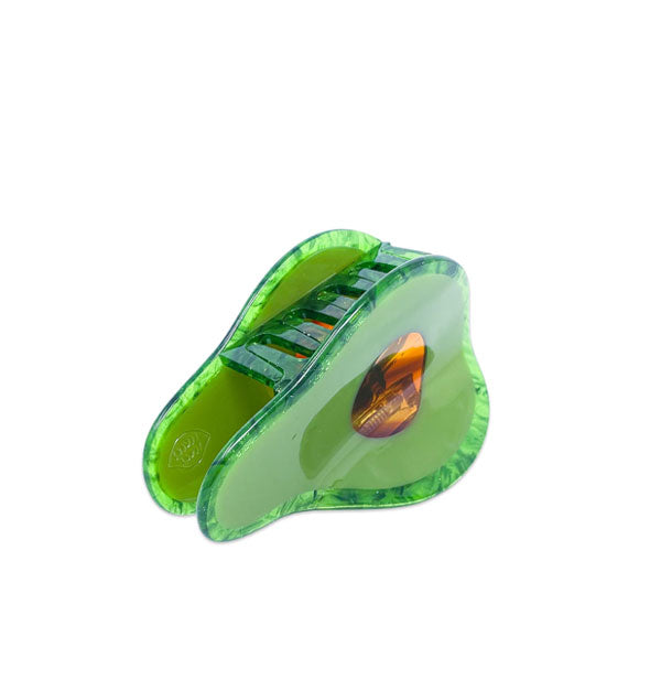 Green hair clip designed to resemble half an avocado with a brown tortoise center and crystal effect green border to represent its skin