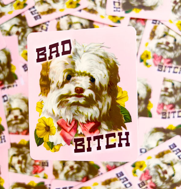 Rectangular pink sticker features a scruffy white and brown puppy illustration with pink bow and yellow flowers between the words, "Bad Bitch"