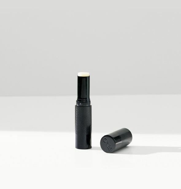 Black tube of Oribe lip balm with white product tip partially exposed
