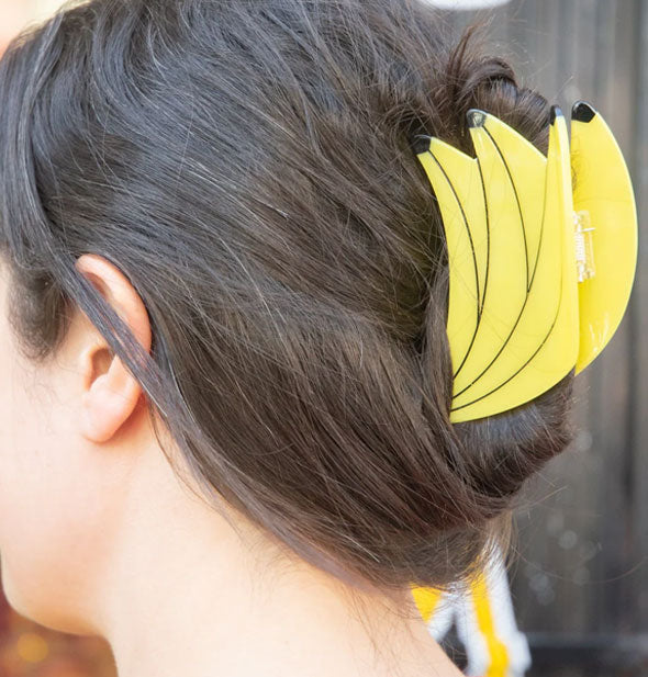 Model wears a banana bunch claw clip in a swept-back hairstyle