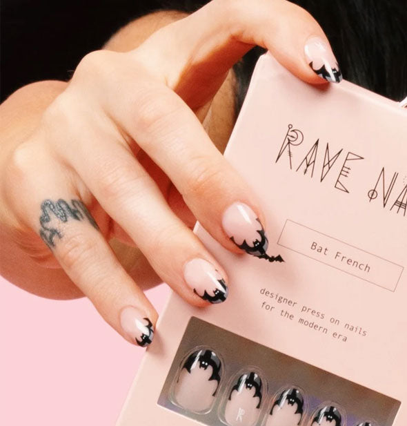Model's hand with Bat French Rave Nails holds a pack of the same kind