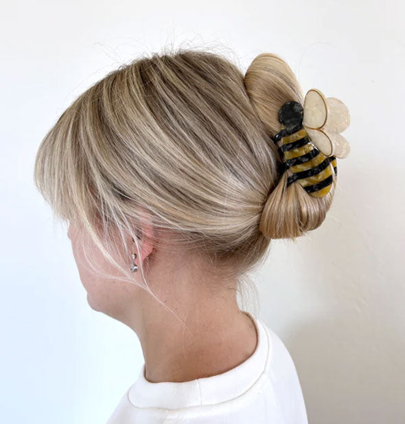 Model wears a bumblebee hair clip in a twist updo