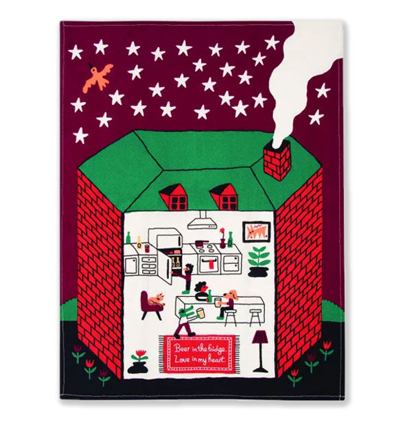 Dish towel with illustration of a cut-away brick home with people and animals inside and smoke pouring out of the chimney features stars in a dark sky with bird and flowers growing on either side of the house