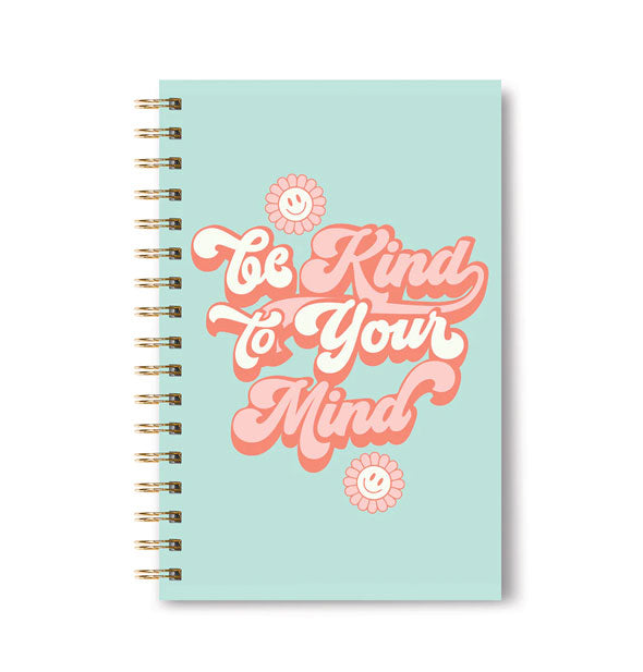 Light blue spiral-bound notebook cover says, "Be Kind to Your Mind" in retro-style white and pink shadowed script with smiley-face flower graphics above and below