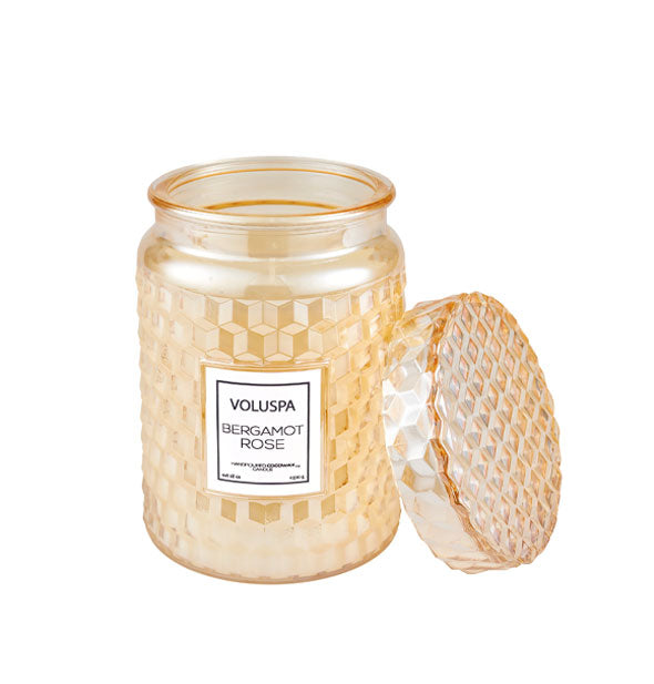 Textured yellow Voluspa Bergamot Rose candle jar with matching lid removed and propped up alongside