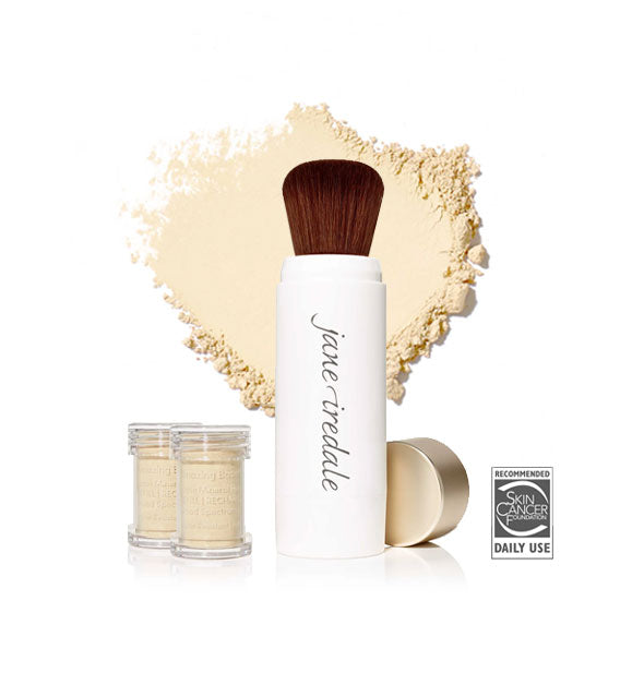 White Jane Iredale powder brush with gold cap removed and set to the side, two refill canisters nearby, and an enlarged product sample in the background in shade Bisque