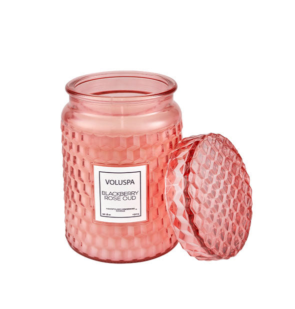 Textured pink Voluspa Blackberry Rose Oud candle jar with matching lid removed and propped up alongside