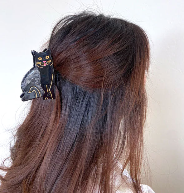 Model wears a black cat hair clip in a partially swept-back style