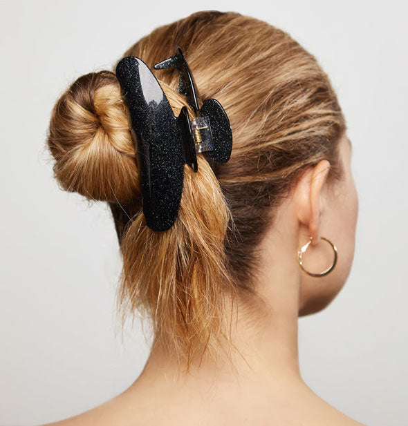 Model wears a black glitter finish claw clip in a twisted updo