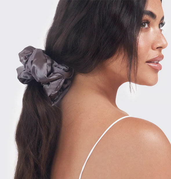 Model wears a pillowy gray satin hair scrunchie in a low ponytail