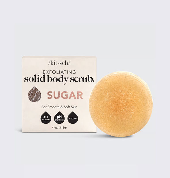 Round amber-colored Solid Body Scrub Sugar bar by Kitsch next to packaging