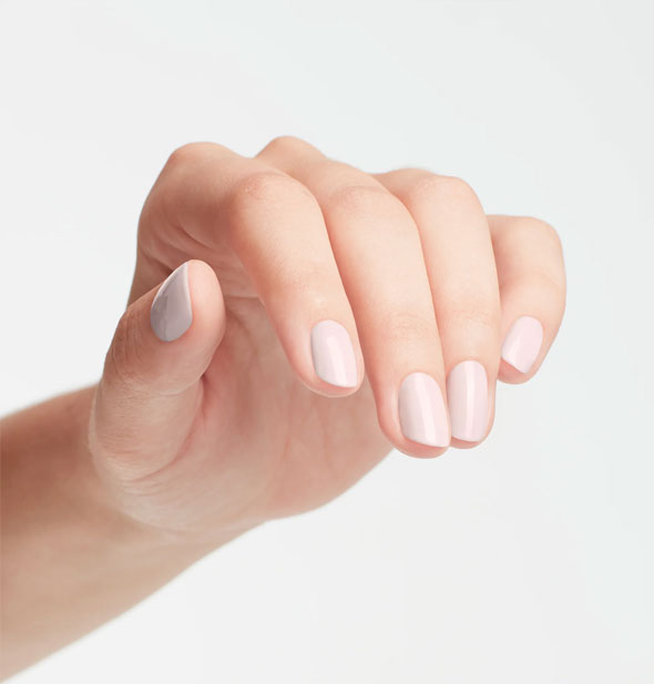 Model's hand wears a very pale shade of pink nail polish