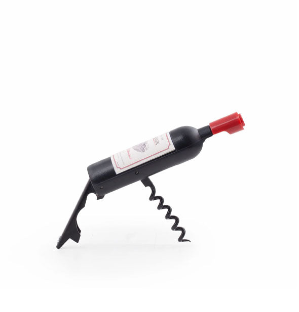 A wine bottle opener resembling a miniature wine bottle is propped up on its built-in a bootlever and corkscrew