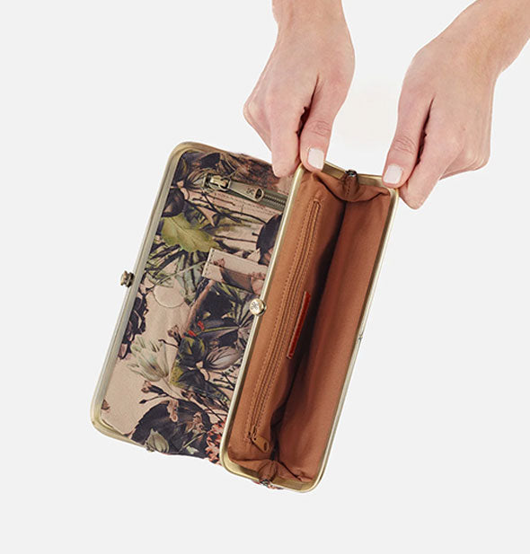Model's hands hold open a section of a floral wallet to reveal brown lining and additional zipper pocket inside