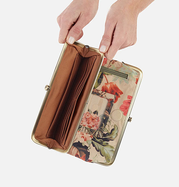 Model's hands hold open a floral wallet to reveal brown lining with storage slots inside