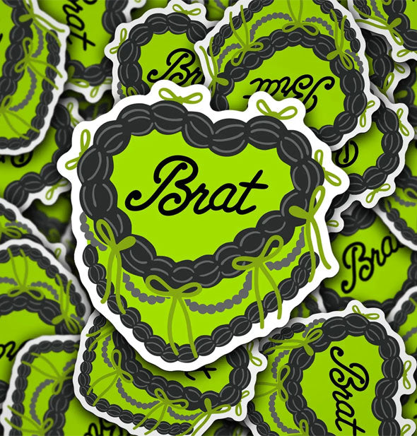 Smattering of stickers designed to resemble green heart-shaped cakes with ornate icing that say, "Brat" on top in script lettering