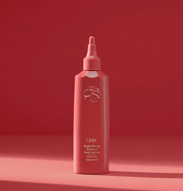 Coral-colored 5.9 ounce bottle of Oribe Bright Blonde Radiance & Repair Treatment with targeted nozzle