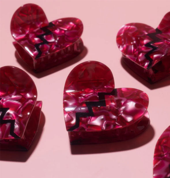 Dark pink quartz-effect broken heart hair clips grouped together on a light pink surface