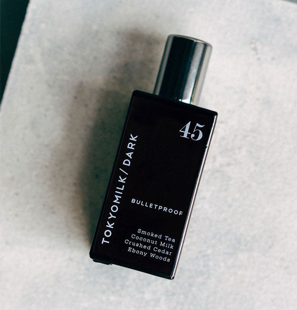 Black rectangular TokyoMilk/Dark Bulletproof perfume bottle on its side on a granite surface
