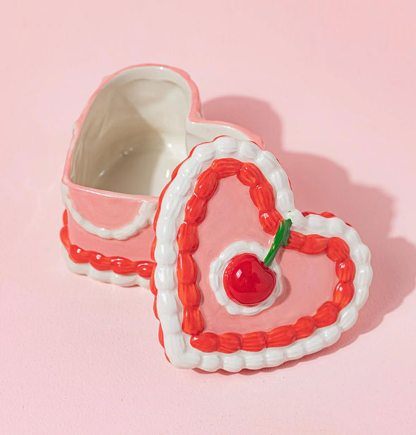 Pink, red, and white heart-shaped ceramic cake jewelry box with cherry-adorned lid removed to show interior