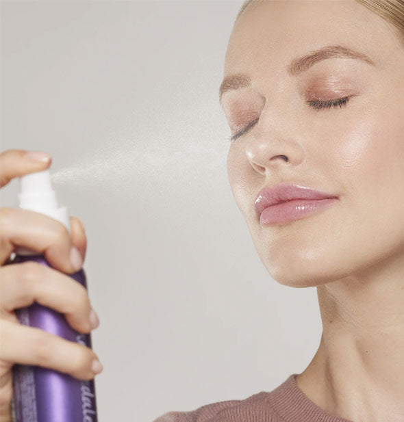 Model with eyes clothes demonstrates application of Jane Iredale Calming Lavender Hydration Spray