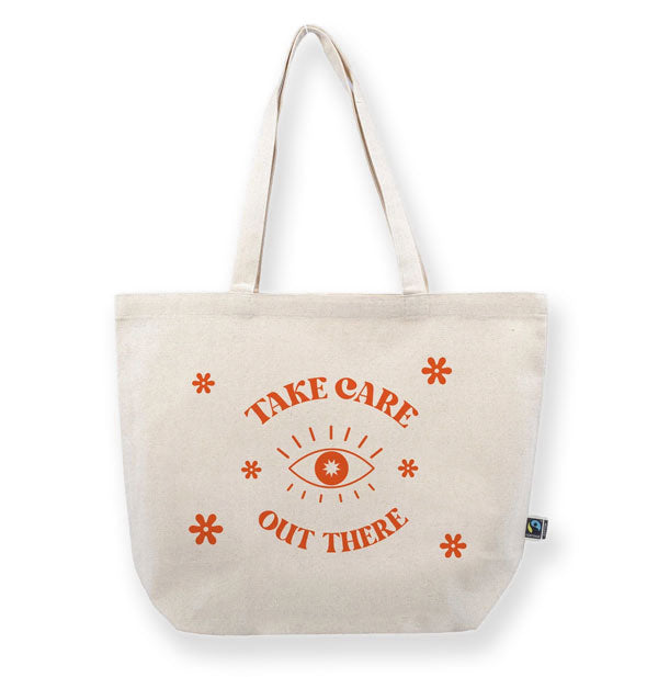 White canvas tote bag says, "Take care out there" with eye illustration and star accents in red