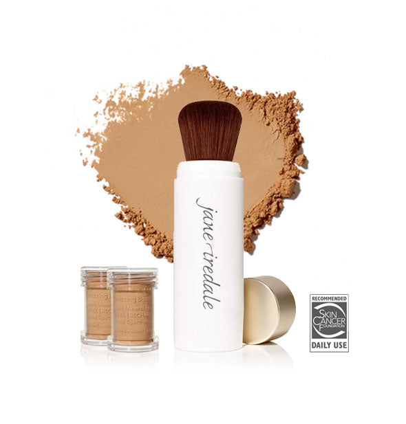 White Jane Iredale powder brush with gold cap removed and set to the side, two refill canisters nearby, and an enlarged product sample in the background in shade Caramel