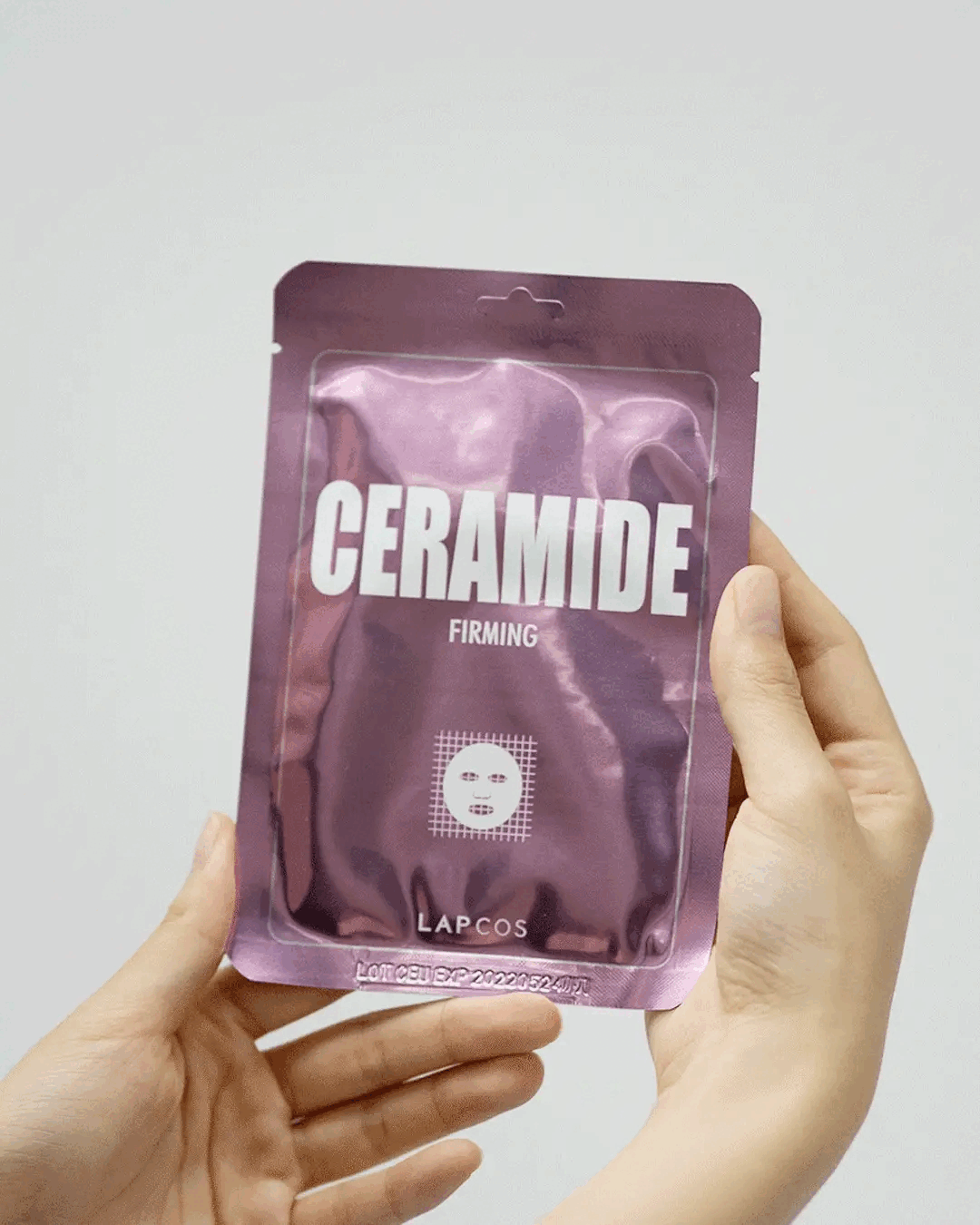 Model removes Ceramide Firming sheet mask from packet and unfolds it
