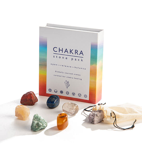 An arrangement of colorful stones with muslin drawstring bag to the side sits alongside an upright box that says, "Chakra Stone Pack."