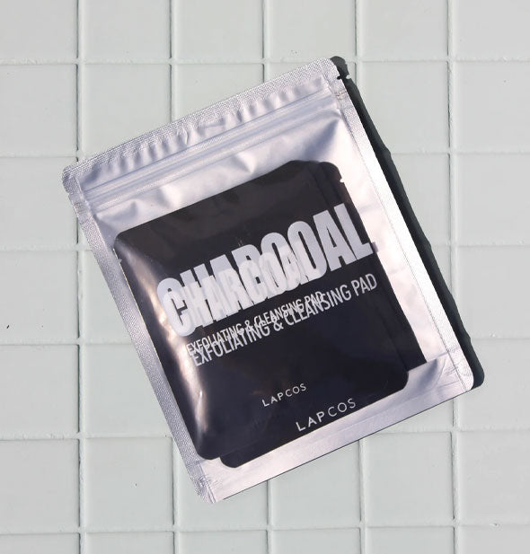 Lapcos Charcoal Exfoliating & Cleansing Pad packet on white tiled surface