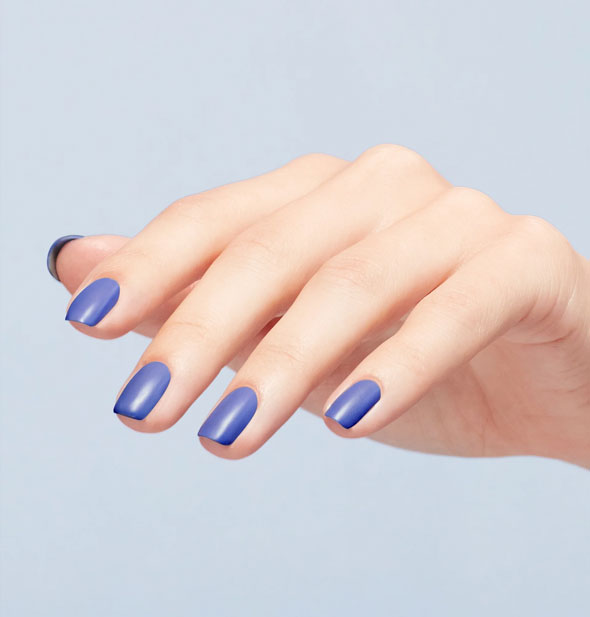 Model's fingernails are painted with a dark shade of periwinkle nail polish