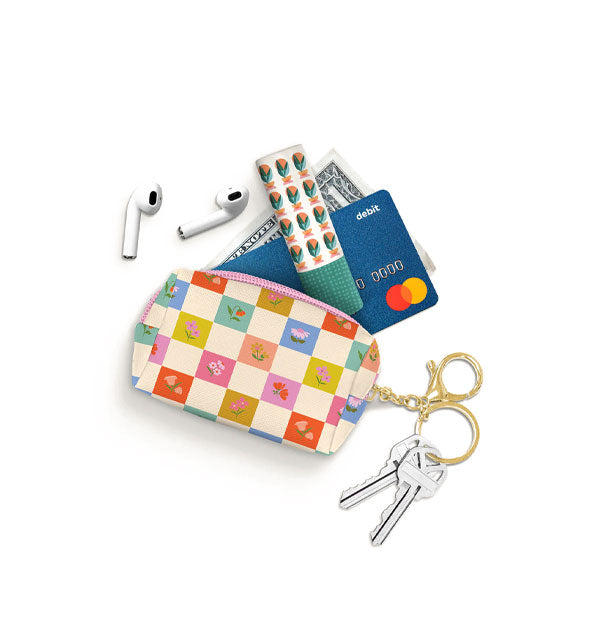 Checkered floral keychain pouch spills out its contents: earbuds, lip balm, credit card, and dollar bill