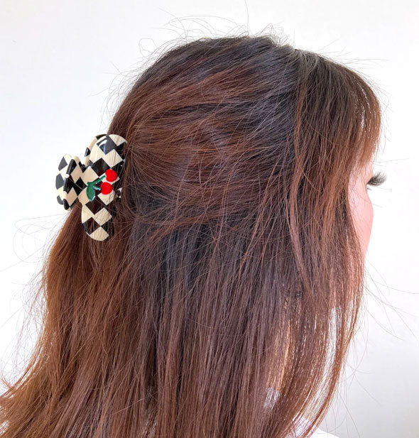 Model wears a black & white checkered claw clip with red cherries in a partially swept-back hairstyle