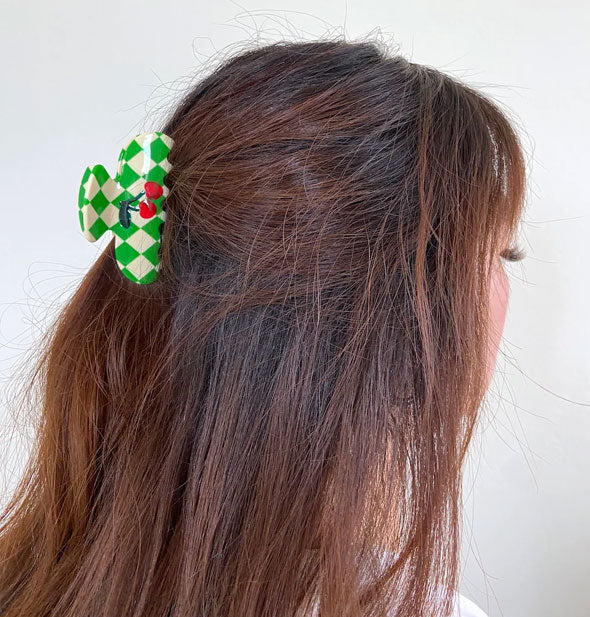 Model wears a green & white checker print claw clip with cherries decal in a partially swept-back hairstyle