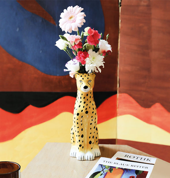 Cheetah flower vase staged against a colorful backdrop holds a bouquet of pink, white, and red flowers