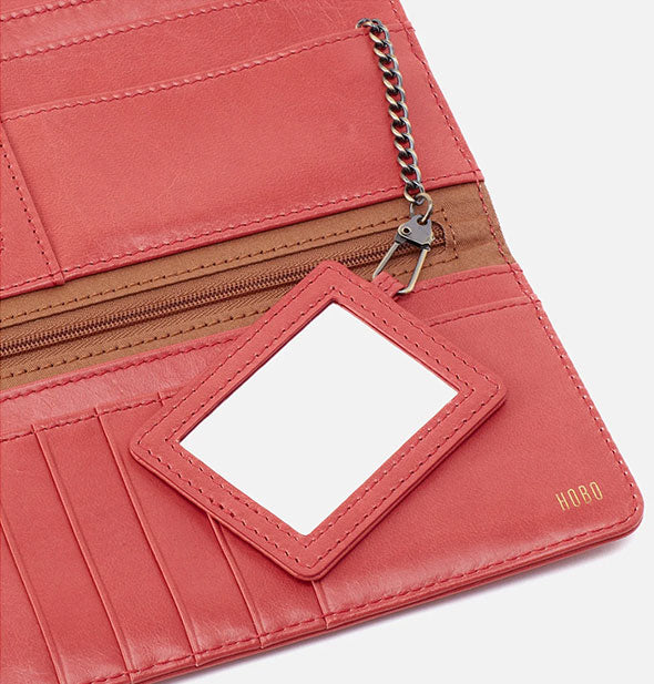 Closeup of salmon-colored leather wallet interior with mirror attached to an antiqued brass chain