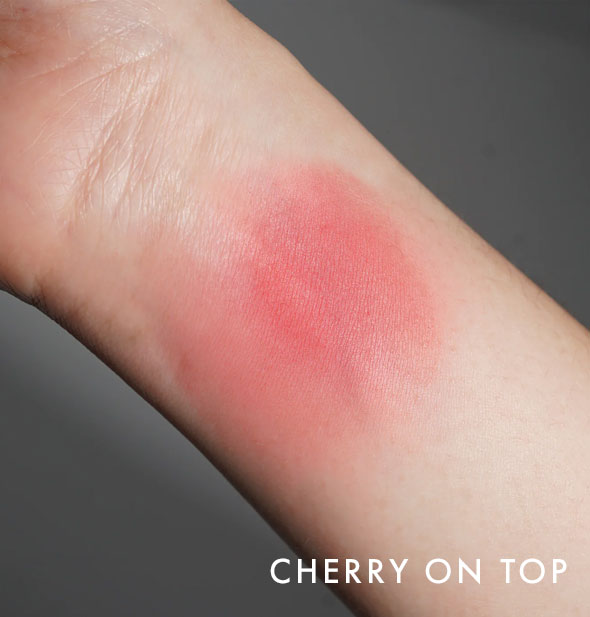 Kara Beauty Soft Serve Lip & Cheek Whip shade Cherry on Top is applied to the inside of a model's wrist