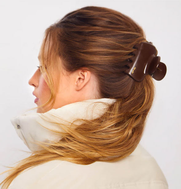 Model wears a large chocolate brown claw clip in a messy ponytail